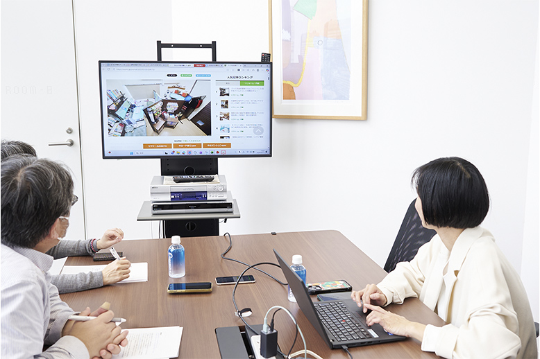 パーティーションで自宅の一角を仕切り、夫妻のワークスペースをつくった記事について説明中の福澤さん。