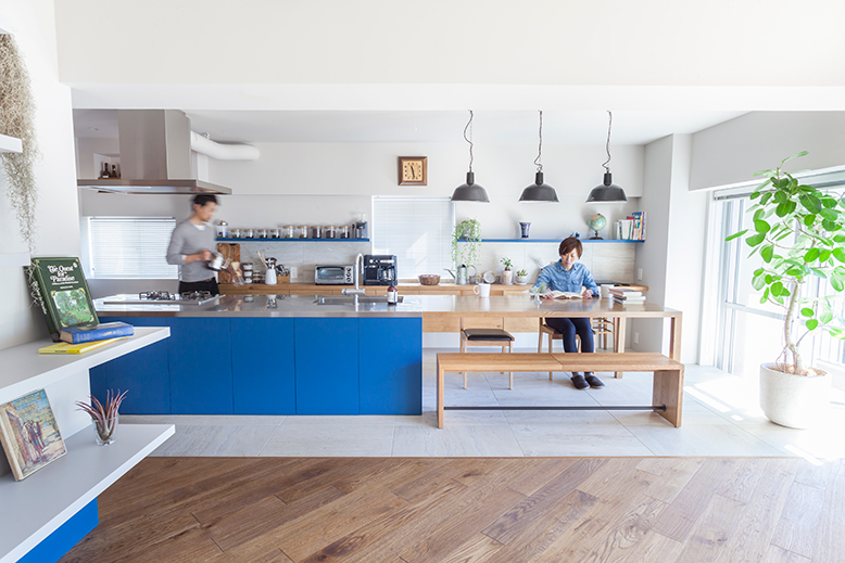ブルーのキッチンを床の白いタイルと木目のテーブルが引き立てます。