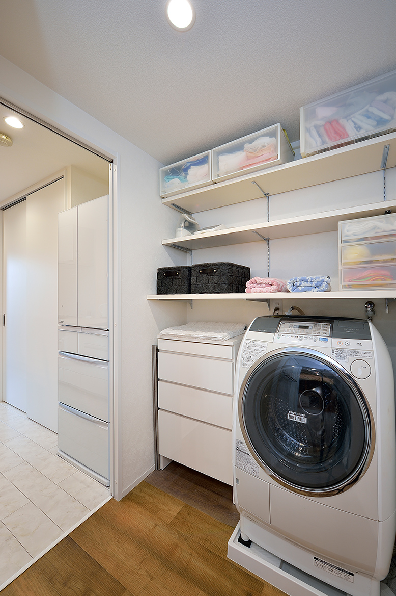 家事動線を短くするため、洗濯機を置いた洗面所をキッチンのすぐ隣に配置。洗濯機上部も活用し可動棚など収納を設けて、片付けやすくしました。