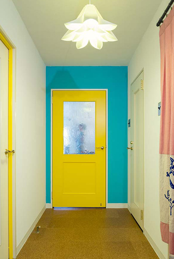 色で遊んだという廊下まわり。壁のほかドア枠、巾木、照明を白にするなどして、鮮やかなイエロー、ブルーを上手に引き立てています。左手のドアは枠のみがイエロー。